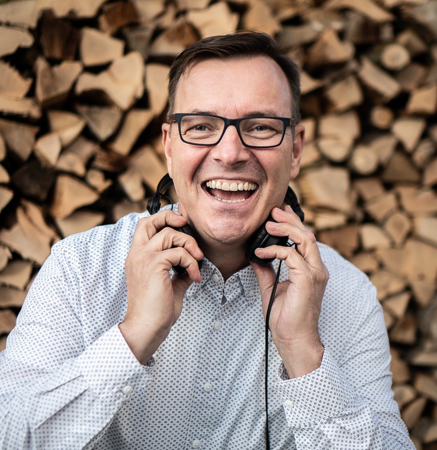 Ernst Limmer alias DJ Erny lacht mit Kopfhörern um den Hals