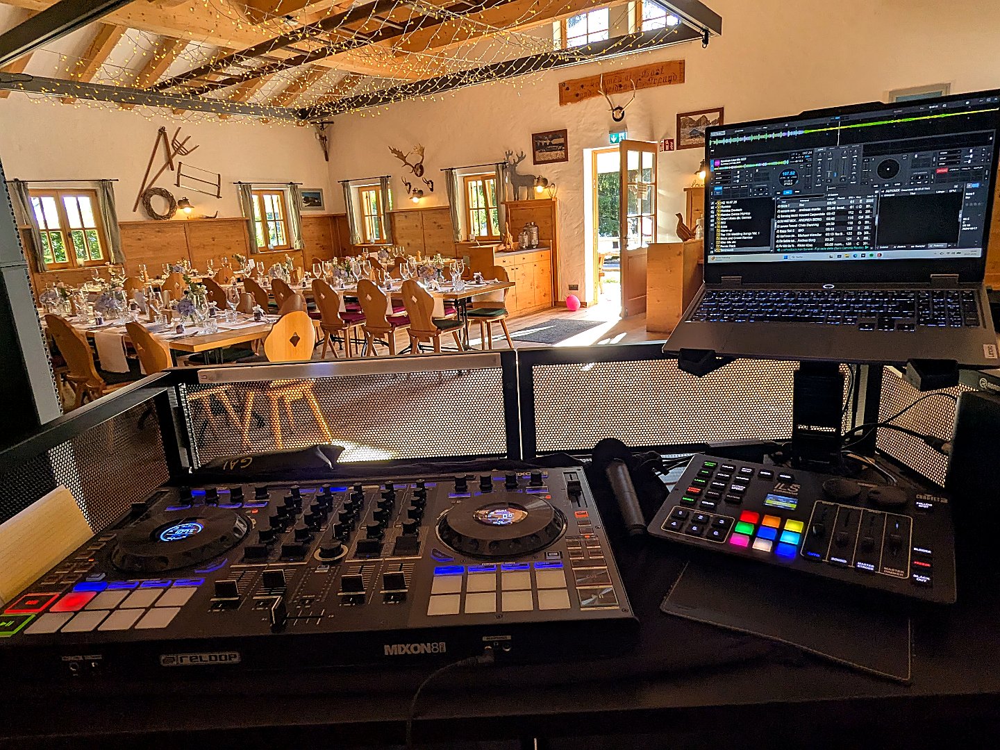 DJ-Pult in einer mit Lichterketten geschmückten, lichtdurchfluteten Scheunen-Location
